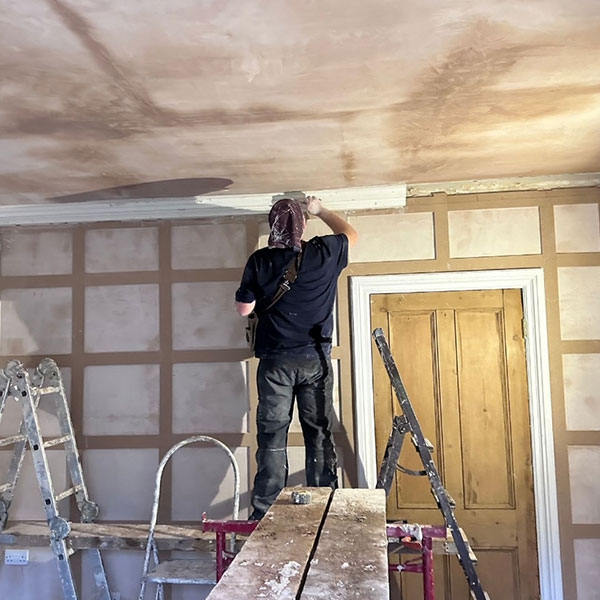 Plasterer working on house ceiling